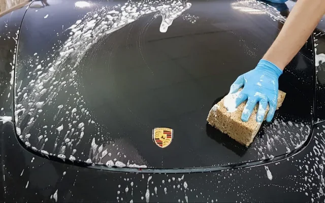 Handwäsche auf der Fronthaube eines schwarzen Porsche