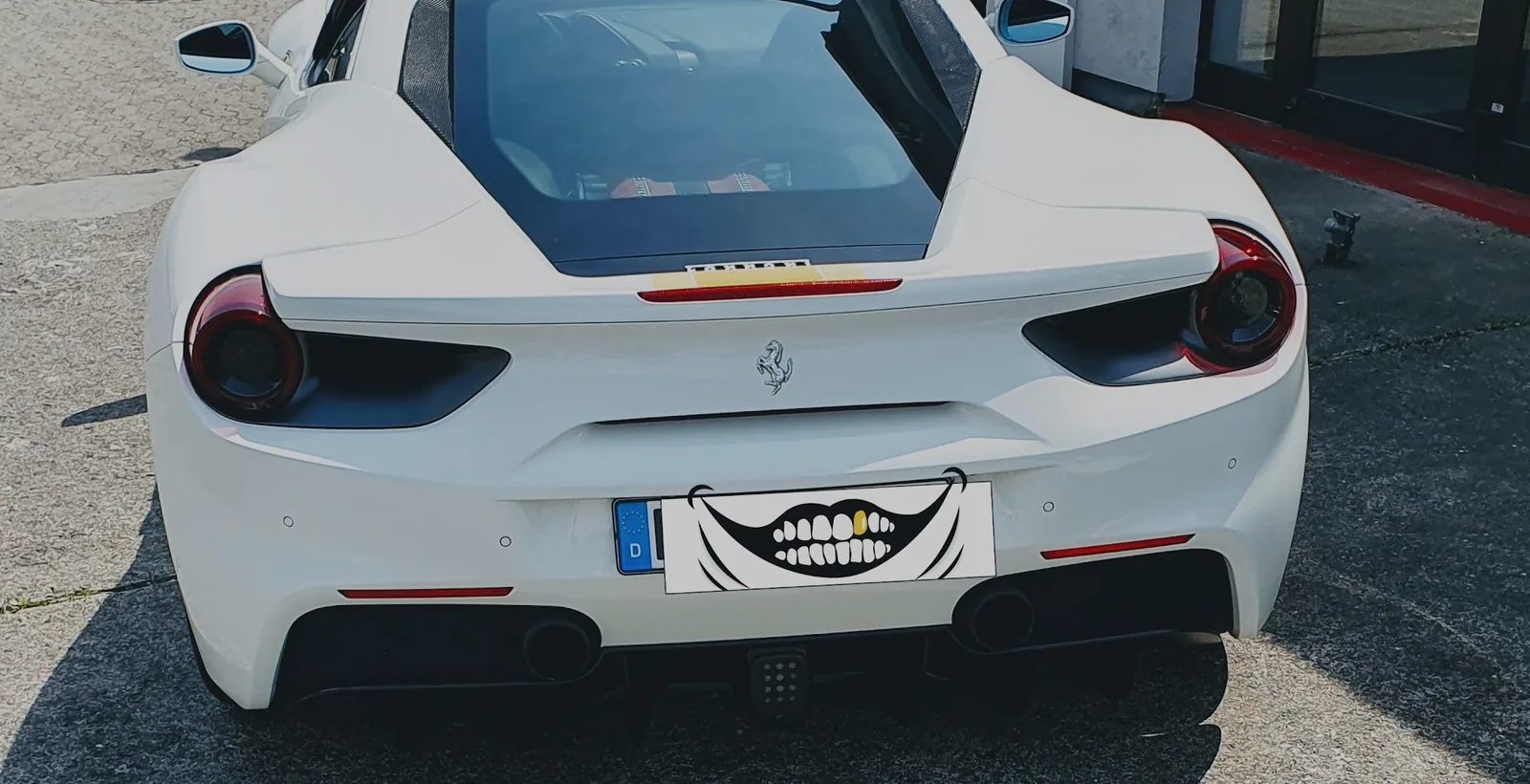 Weißer Ferrari 488 von hinten auf dem Hof der Werkstatt